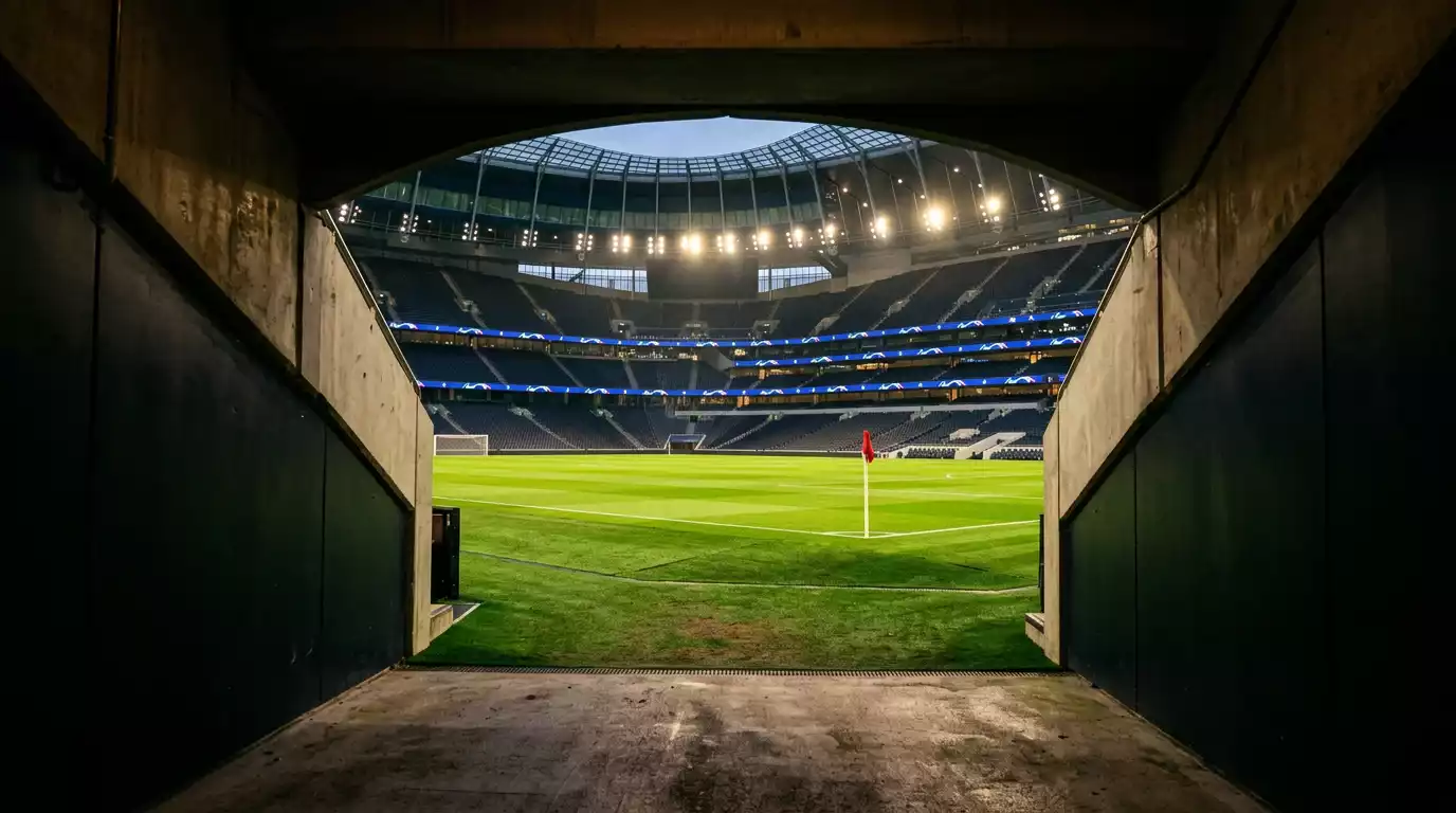 Vestuario y túnel de acceso al campo de un estadio antes de un partido de fútbol, con el césped iluminado al fondo esperando la salida de los equipos