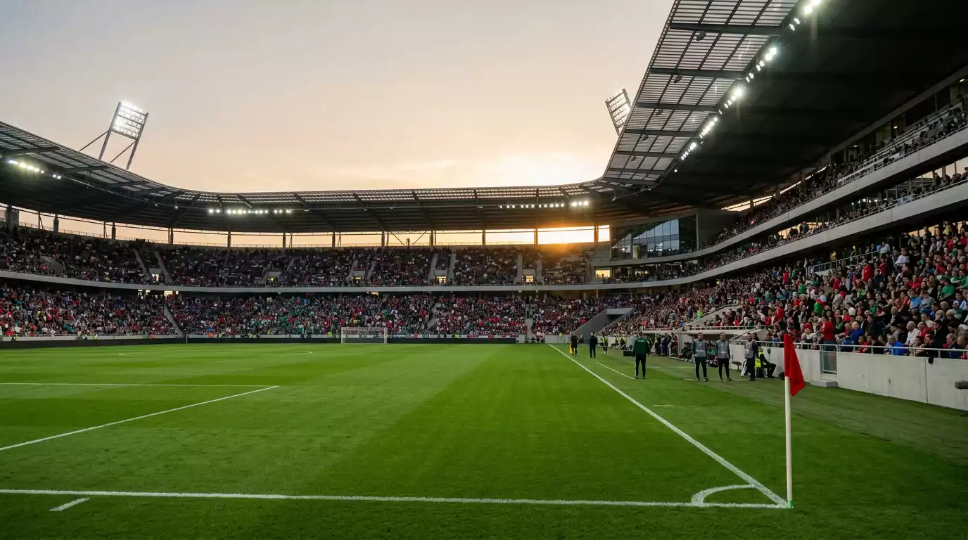 Estadio de fútbol con el césped iluminado antes de un partido de los dieciseisavos del Mundial 2026, gradas llenándose bajo la tarde de verano